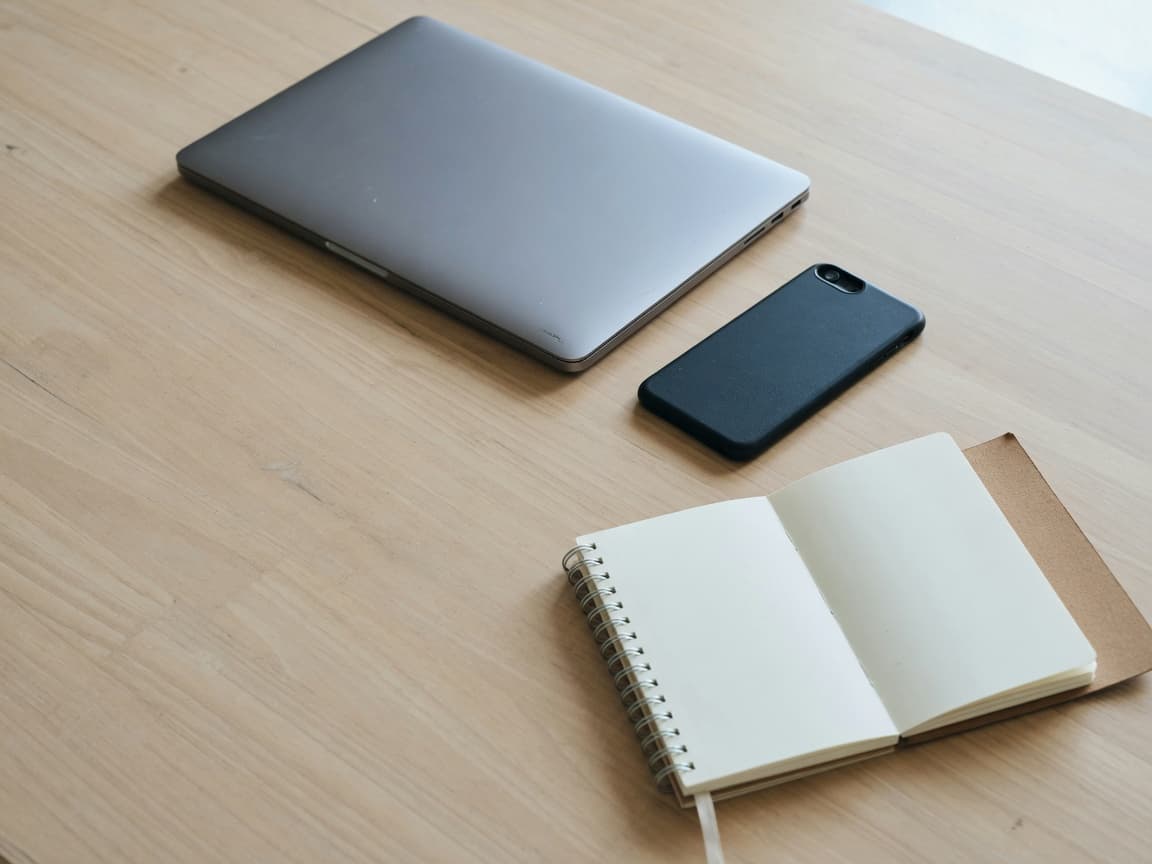 A laptop and a phone on a desk.